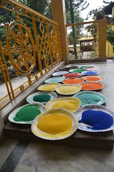Coloured mandala sands arranged on plates at Sed Gyued Monastery, beside a golden Dharma-wheel railing